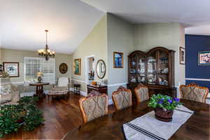 Dining space with dark wood-style flooring, high vaulted ceiling, and a chandelier