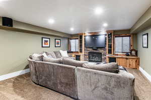 Carpeted living area with a stone fireplace and recessed lighting