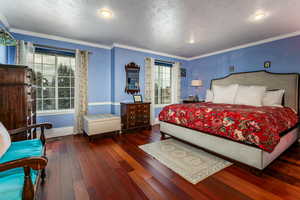 Bedroom with ornamental molding, dark wood-type flooring, a textured ceiling, and recessed lighting