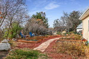 View of yard featuring a garden and view of wooded area