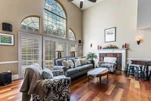 Living area featuring a high ceiling, a tile fireplace, wood finished floors, and a ceiling fan