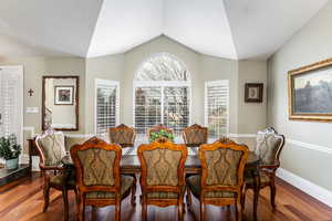 Dining area with dark wood-style flooring and lofted ceiling