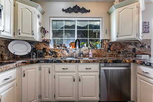 Kitchen with dishwasher, tasteful backsplash, and white cabinetry