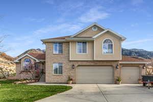 Traditional-style home featuring brick siding, driveway, a mountain view, an attached garage, and stucco siding