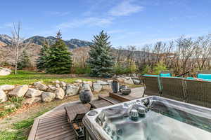 View of patio / terrace with a hot tub and a deck with mountain view