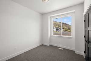 Empty room featuring dark colored carpet and a mountain view