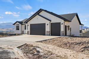 Modern inspired farmhouse featuring a mountain view, an attached garage, driveway, board and batten siding, and roof with shingles