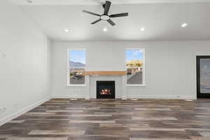 Unfurnished living room featuring plenty of natural light, recessed lighting, a glass covered fireplace, and dark wood-type flooring