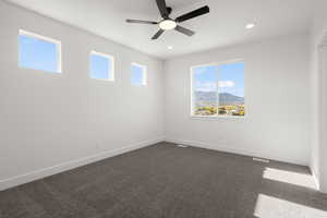 Unfurnished room with dark colored carpet, ceiling fan, a mountain view, and recessed lighting