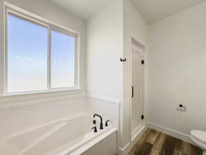 Full bathroom featuring dark wood-style floors, a marble finish shower, and a bath