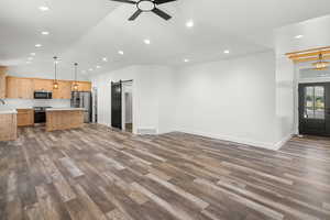 Unfurnished living room featuring a barn door, dark wood finished floors, recessed lighting, lofted ceiling, and a ceiling fan