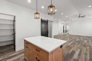 Kitchen featuring recessed lighting, pendant lighting, a barn door, a kitchen island, and dark wood-style floors