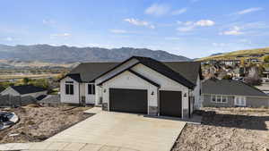 Modern inspired farmhouse with a mountain view, stone siding, driveway, and a garage