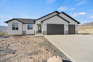 Modern farmhouse featuring a mountain view, driveway, a garage, board and batten siding, and stone siding