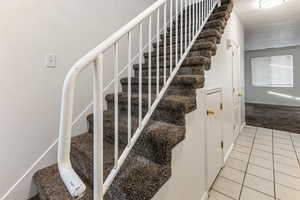 Stairway with baseboards and tile patterned floors
