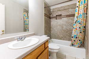 Full bath with vanity, shower / bath combo with shower curtain, a textured ceiling, and light tile patterned floors