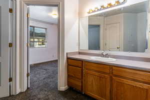 Bathroom with vanity and dark carpet