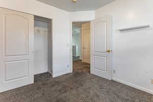 Unfurnished bedroom with dark carpet and a closet