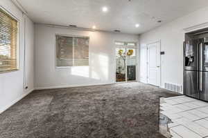 Unfurnished room with carpet, recessed lighting, tile patterned flooring, and a textured ceiling
