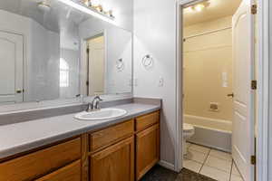 Full bath featuring vanity, light tile patterned floors, and bathing tub / shower combination