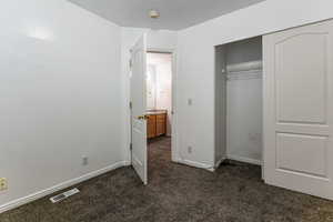 Unfurnished bedroom with dark colored carpet and a closet