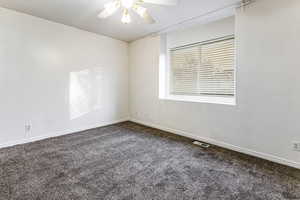 Spare room with dark colored carpet and a ceiling fan