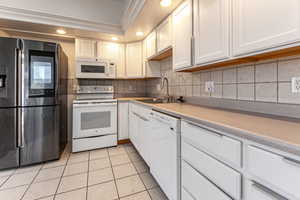 Kitchen with recessed lighting, white appliances, light countertops, white cabinetry, and light tile patterned floors