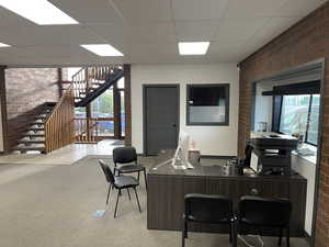 Office with brick wall and a paneled ceiling