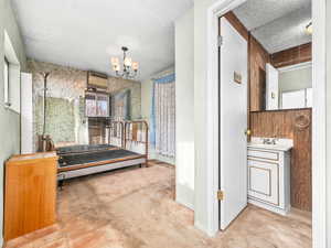 Bedroom featuring light colored carpet, multiple windows, a chandelier, a textured ceiling, and wallpapered walls