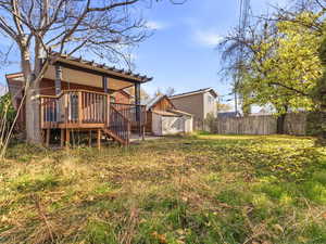 Back of house with a deck, stairway, a fenced backyard, brick siding, and an outdoor structure