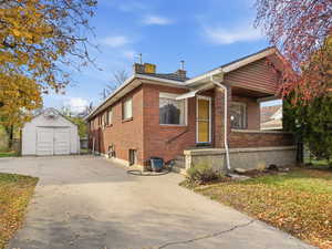 Bungalow-style home with an outdoor structure, brick siding, and a chimney