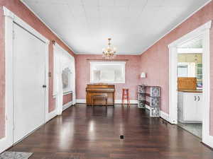 Dining area featuring wood finished floors, a chandelier, healthy amount of natural light, and ornamental molding