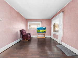 Living area with dark wood-style floors, ornamental molding, and a textured wall