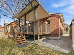 Back of house with brick siding and a wooden deck