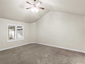 Carpeted spare room with lofted ceiling and ceiling fan