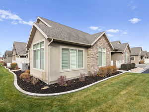 View of side of property with a yard, stone siding, and a residential view