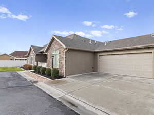 Ranch-style house with stone siding, concrete driveway, roof with shingles, stucco siding, and an attached garage