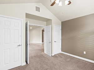 Unfurnished bedroom with light carpet, a ceiling fan, and high vaulted ceiling
