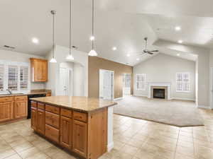 Kitchen with light tile patterned floors, hanging light fixtures, a center island, arched walkways, and a fireplace
