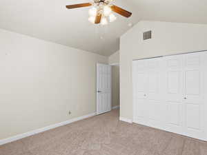 Unfurnished bedroom with lofted ceiling, carpet flooring, a closet, and a ceiling fan