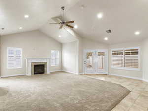 Unfurnished living room featuring high vaulted ceiling, a fireplace, recessed lighting, ceiling fan, and light carpet