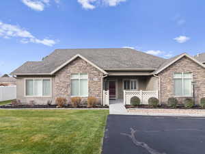 Single story home with stone siding, roof with shingles, and stucco siding