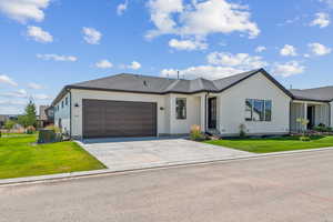 View of front of home featuring a front lawn, a shingled roof, driveway, and an attached garage