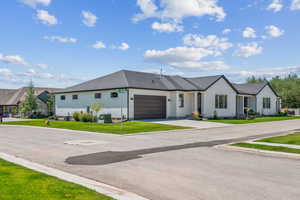 View of front of house with an attached garage, driveway, and a front lawn