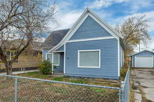 View of property exterior with a fenced front yard, a detached garage, an outdoor structure, and driveway