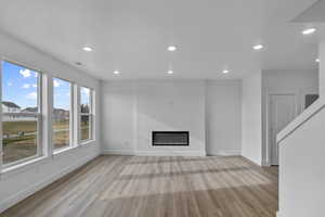 Unfurnished living room featuring recessed lighting, light wood-type flooring, and a glass covered fireplace