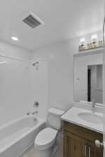 Bathroom featuring washtub / shower combination, vanity, light tile patterned floors, and a textured ceiling