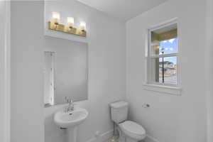 Half bath featuring toilet and baseboards