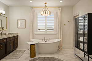 Full bathroom with a freestanding bath, a chandelier, vanity, and recessed lighting