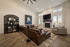 Living area featuring high vaulted ceiling, a fireplace, dark wood-style flooring, recessed lighting, and ceiling fan